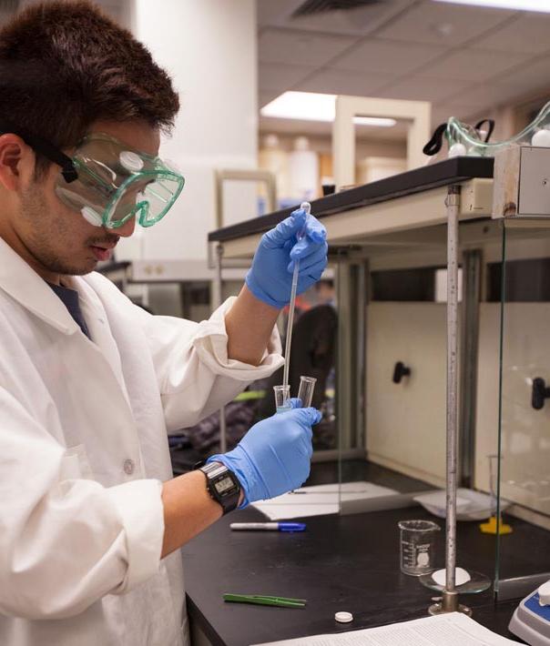 student in lab coat with experiment